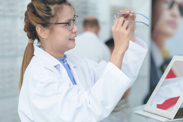 Wall Mural - Female ophthalmologist holding eyeglasses and examining them, focus on eyeglasses, close-up