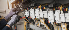 Electricity And Electrical Maintenance Service, Engineer Hand Holding AC Multimeter Checking Electric Current Voltage At Circuit Breaker Terminal And Cable Wiring Main Power Distribution Board.