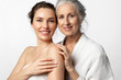 Two tender beautiful women of different ages and generations together on a white background. The daughter and her elderly mother are smiling.