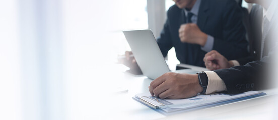 Two businessmen having a discussion, working on laptop computer, using digital tablet and mobile phone during meeting at office. Business planning and solution, working together concept