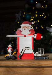 Wall Mural - toy miniature excavators, a souvenir snowman, a notebook with Santa Claus, a funny pen on background of Christmas tree