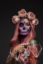 Portrait Of Halloween Style Evil Woman With Makeup And Bat Skeleton Against Grey Background.