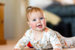 © Austockphoto - happy five month old baby girl with blue eyes learning to crawl on floor