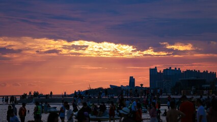 Poster - Silhouettes of people relaxing on beach, on embankment under orange sunset sky