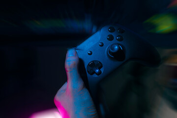 gamer playing the online game with joystick controller in neon glow dark cyberpunk room, gaming and e-sports challenge tournament streaming, streamer with analog device in living house