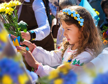 Ukrainian Schoolgirl In A Wreath And Embroidered Shirt And With Patriotic Flowers Against The War In Ukraine