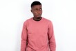 © Jihan - Amazed puzzled young handsome man wearing pink sweater over white background, curves lips and has worried look, sees something awful in front.