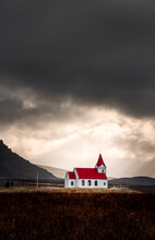 The Classic Small Red Church Reyniskyrka In Dramatic Weather With Sun Breaking Through. Just Outside Of Vik, Iceland.