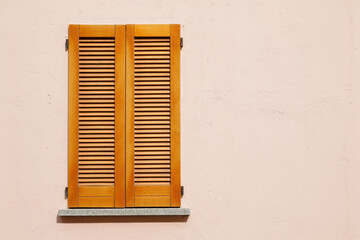 Beautiful wooden window shutter with windowsill, rosa painted cement wall and sunny day