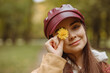 © Dzmitry - Portrait of smiling woman covering eye with yellow flower while hiding and looking at camera in nature in autumn