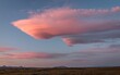 Big pink cloud in a sunset sky over a beautiful field with mountains in the background in Iceland