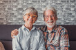 Portrait of couple of mature people wearing glasses and looking at the camera together. Close up of two seniors sitting on the sofa having fun and enjoying.