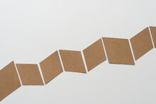 Brown Paper Shapes Arranged In Accordion Or Chevron Or Zig Zag Form Across A Blank Paper Background
