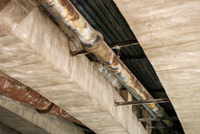 Large Rusty Pipes Under A Bridge In Poor Condition.