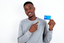 Photo Portrait Of Young Handsome Man Wearing Grey Sweater Over White Background Doing Purchase With Pointing Finger Credit Bank Card