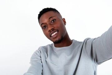 Photo of young handsome man wearing grey sweater over white background do selfie