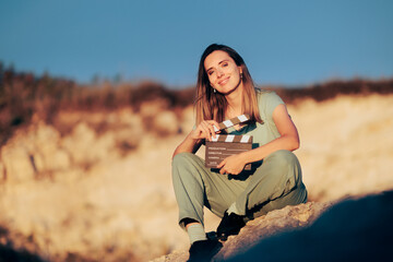 Canvas Print - Beautiful Actress Holding a Film Slate in Natural Outdoors Set. Confident actor shooting a scene in nature at golden hour sunlight
