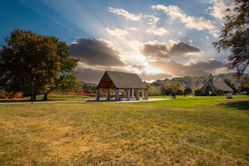 Wall Mural - a gorgeous autumn landscape at Lakeshore Park with a brown wooden and stone pergola surrounded by autumn colored trees and lush green trees and grass with powerful clouds at sunset in Knoxville