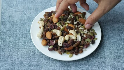 Wall Mural - hand pick many mixed nuts from a plate 