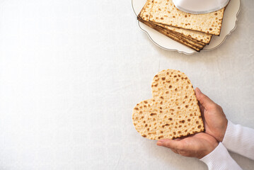 Wall Mural - Woman's hands holds Matzah shape of heart. Traditional of Jewish Holiday on Passover. Home symbol of lovely family. top view, layout. love and care. Gift for lovers. Feeling in love and blissful life