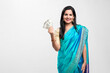 Indian woman in saree and showing money on white background.