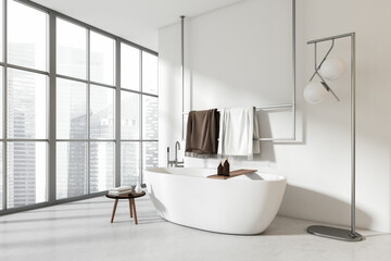 Light bathroom interior with tub and accessories, panoramic window