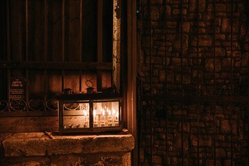 Sticker - Container with candles glowin in it in front of an  old window