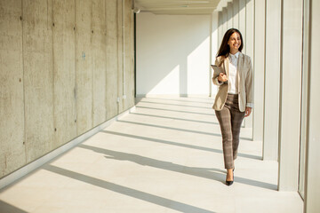 Wall Mural - Young businesswoman walking on modern office hallway