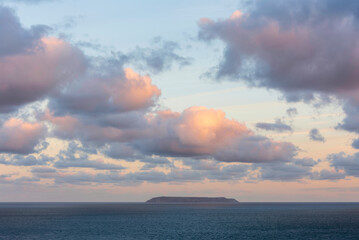 Wall Mural - Beautiful sunrise clouds formations and colour over Lundy Island on Devonshire coast in England during late Summer