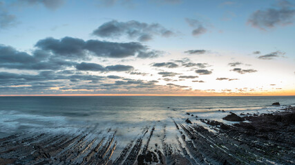 Wall Mural - Beautiful sunset landscape image of Welcome Mouth Beach in Devon England with beautiful rock formations