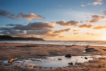 Wall Mural - Stunning Summer sunset landscape image of Widemouth Bay in Devon England with golden hour light on beach