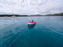 Red Dinghy Trailing By A Rope In Blue Water