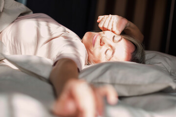 Wall Mural - Happy middle aged woman sits on bed and stretching arms