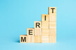 merit - text on a pyramid of wooden cubes, blue background