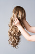 © staras - Curly blonde wig close-up on a gray background