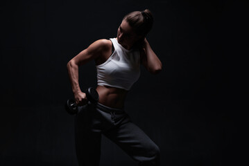 Athletic fitness woman posing in the studio on a dark background. Photo of an attractive woman in fashionable sportswear. Sports and healthy lifestyle