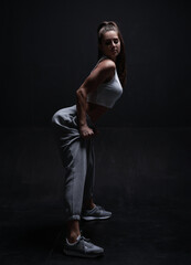 Athletic fitness woman posing in the studio on a dark background. Photo of an attractive woman in fashionable sportswear. Sports and healthy lifestyle