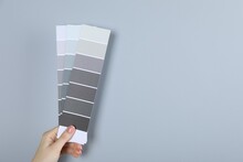 Woman With Paint Chips Choosing Color Near Grey Wall, Closeup. Interior Design