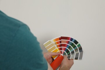 Poster - Man with palette choosing color for painting wall indoors, closeup. Interior design