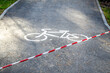 © Ninaveter - asphalt bike path fenced with red and white protective tape. Fenced area in the park, prohibition of movement. Closed Dedicated track for cyclists