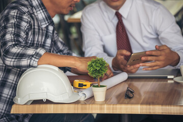 Asian engineer man brainstorming construction building contractor civil worker parners team meeting at constrcution site. Blueprint engineer hardhat worker helmet on table. Engineer teamwork consult