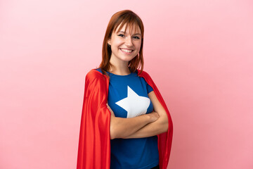 Wall Mural - Super Hero redhead girl isolated on pink background with arms crossed and looking forward