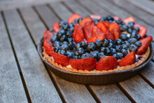 Fresh Homemade Beautiful Fruit Tart With Blueberries And Sliced ​​strawberries On Top On A Wooden Table