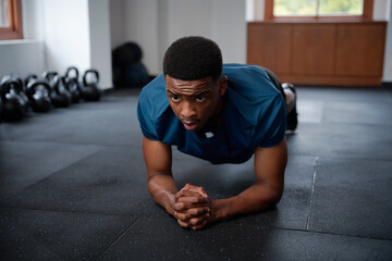 Athletic young black man in sportswear doing plank exercises at the gym