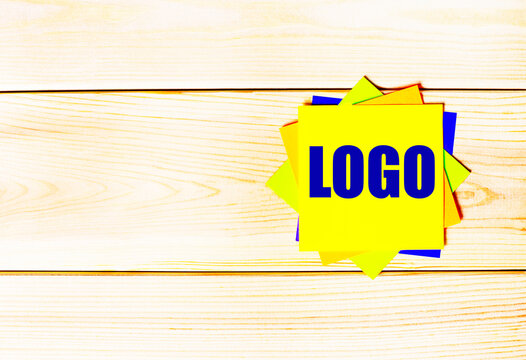 Multicolored office paper stickers with the text LOGO on a wooden background. copy space