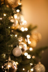 close up view of beautiful fir branches with shiny golden bauble or ball, xmas ornaments and lights,