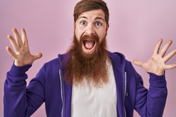 Sticker - Caucasian man with long beard standing over pink background celebrating crazy and amazed for success with arms raised and open eyes screaming excited. winner concept