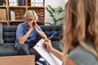 Young blond man patient stressed sitting on sofa at psychology clinic