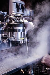 Sticker - Vertical shot of a barista working with a steaming coffee machine