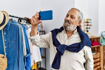 Poster - Senior grey-haired man making selfie by the smartphone at clothing store